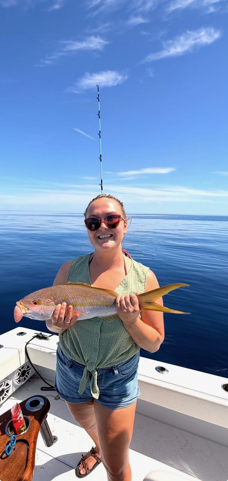 Guest holding a yellowtail snapper offshore with Inverted Fishing Charters